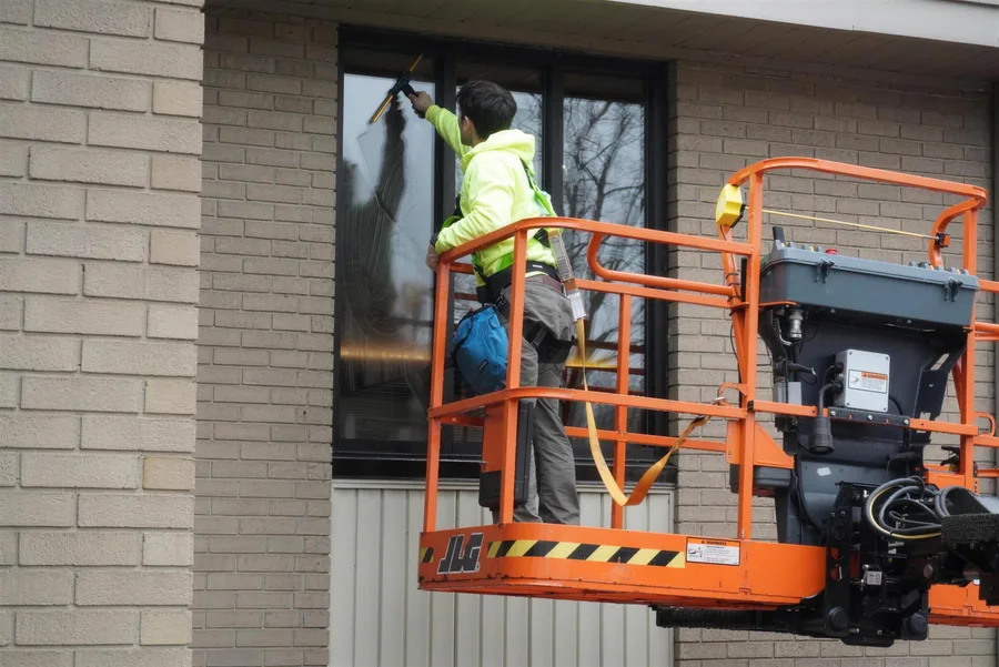Go To Cleaning technician on a lift cleaning commercial storefront windows