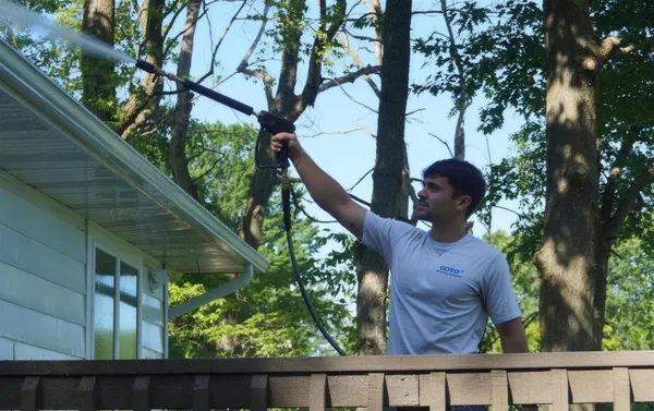 Go To Cleaning technician power washing a home's siding from the deck