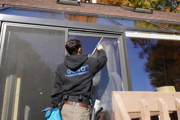 Go To Cleaning technician squeegeeing a large glass door